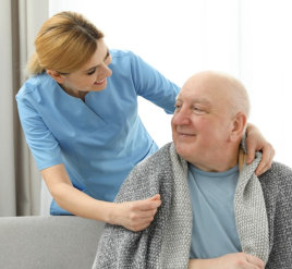 a caregiver woman smiling with an elderly man on a sofa