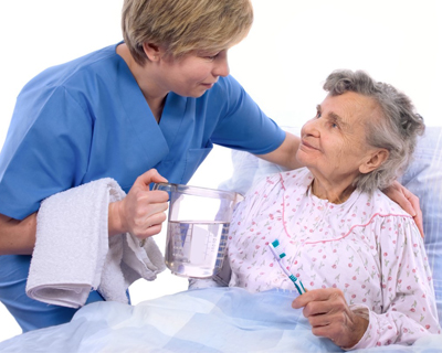 physician attending to elderly woman lying on bed